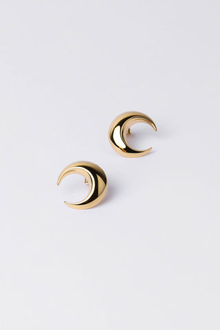 A pair of gold crescent moon hoop earrings on a clean, light gray background.