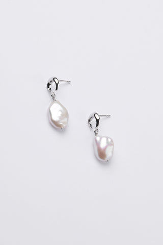 A pair of silver moon shape baroque pearl drop earrings on a clean, light gray background.