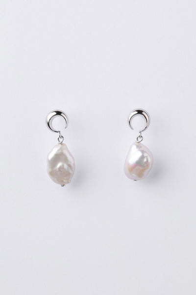 A pair of silver moon shape earrings with irregular white baroque pearls hanging below, displayed on a clean light gray background.