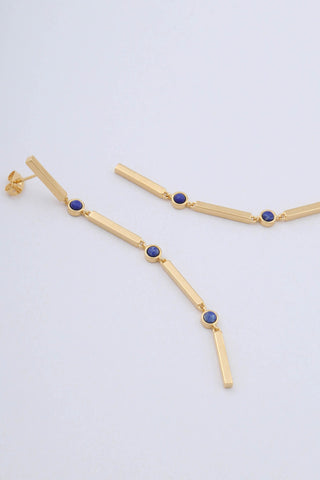 Close up of gold plated long drop earrings by Miro Miro. Featuring interlocking bars and natural lapis lazuli stones set in a bezel fitting.