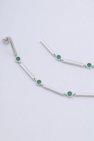 Close up of rhodium plated sterling silver long drop earrings by Miro Miro. Featuring interlocking bars and natural chrysoprase stones set in a bezel fitting.