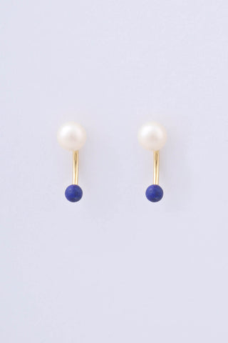 Pair of gold plated earrings by Miro Miro, featuring a freshwater pearl and a spherical natural lapis lazuli stone hanging from a curved ear jacket.