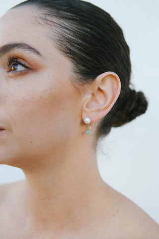 Model wears a rhodium plated sterling silver earring by Miro Miro, featuring a freshwater pearl stud and a curved ear jacket with a spherical natural chrysoprase stone.