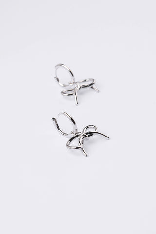 A pair of silver-toned hoop earrings with a small bow charm attached to each hoop, displayed on a clean white background.