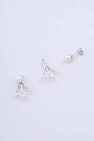 Pair of rhodium plated sterling silver earrings by Miro Miro, showing the natural freshwater pearl stud and removable ear jacket which features three freshwater pearls on a curved pronged finish.