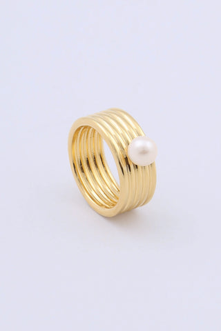 A gold plated ring by Miro Miro, featuring a freshwater pearl set on a thick band with a ribbed textural finish.
