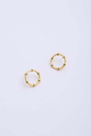 Front facing circular gold earrings, made up of bamboo segments, with green crystals in between them.