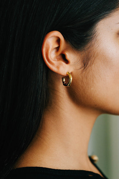 Model wears thick, chunky gold hoops that are in the shape of bamboo segments.