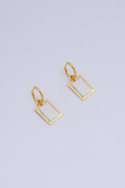 A pair of earrings featuring a rectangular drop shape, made in a two tone gold and silver finish.
