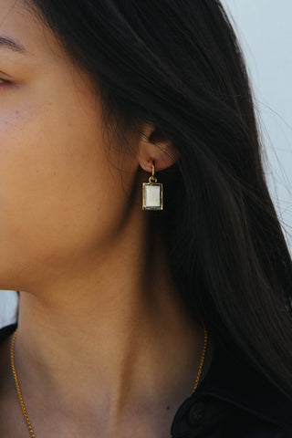 A detail image of an earring featuring a rectangular drop shape, made in a two tone gold and silver finish.