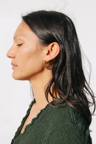 Model wears green top and gold hoop earrings shaped like bamboo.