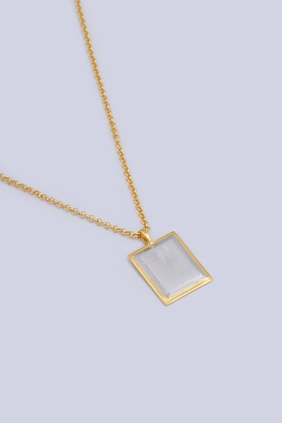 A necklace featuring a rectangular shape pendant, made from a two tone gold and silver finish.