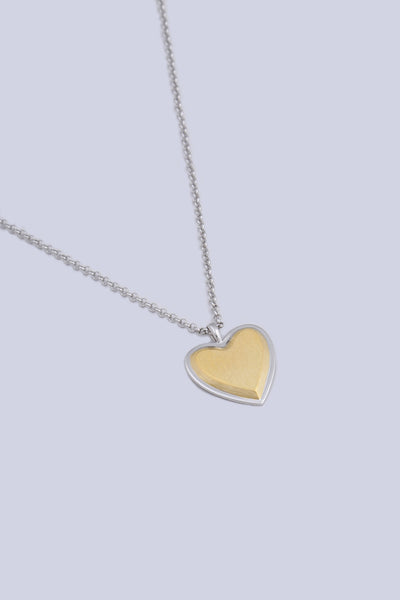 A necklace featuring a heart shape pendant, made from a two tone silver and gold finish.