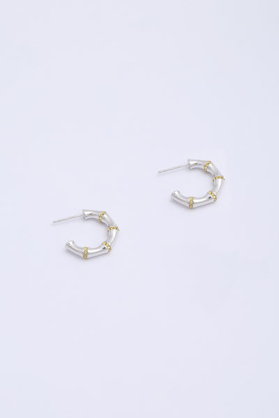 Bamboo shaped silver hoop earrings with small yellow crystals between each node.